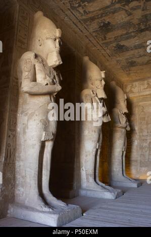 Ägyptische Kunst Großen Tempel von Ramses II (1290-1224 v. Chr.). Grabkunst Tempel in den Fels gehauen. Blick aus dem ersten Raum, mit drei der acht Statuen von Ramses II. als der Gott Osiris. Abu Simbel. Ägypten. Stockfoto