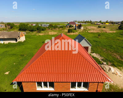 Haus mit einem orangefarbenen Dach aus Metall, Ansicht von oben. Metallische Profil gestrichen Wellpappe auf dem Dach Stockfoto