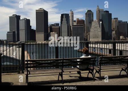 Frau sitzt auf einer Bank in Brooklyn Heights Promenade beobachten die Skyline von Manhattan. New York. USA. Stockfoto