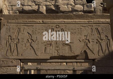 Relief zeigt Gott Amun mit toller Helm mit zwei großen Federn und Bart sitzt auf dem Thron. Ersten Hof des Ramses II. Neuen Imperiums. Tempel von Luxor. Ägypten. Stockfoto