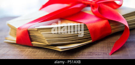 Alte Briefe mit einem roten Band auf alten Holz- Hintergrund, Ansicht von oben, Papier Handwerk gebunden Stockfoto