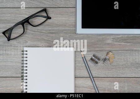 Eine Zwischenablage, eine Brille und eine Tablette auf einem Holztisch Stockfoto