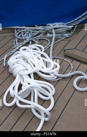 Nahaufnahme einer Verankerung Seil mit einer verknoteten Ende um eine Klampe auf einem hölzernen Pier/Nautische festmacher Seil gebunden. Schließen Boot Seil gebunden auf Abbildung 8 Steckvorrichtung Stockfoto