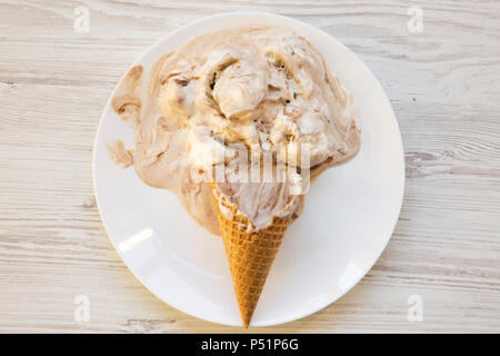 Eis auf einem weißen Teller. Schmelz Schaufeln. Weiß Holz- Hintergrund. Ansicht von oben. Von oben, flach. Stockfoto