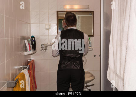 Junger Mann im Badezimmer vor dem Spiegel während der Rasur. Stockfoto