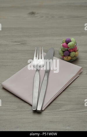 Ein Ostern Ort Einstellung mit einer Serviette, Messer, Gabel und einer Schüssel mit Süßigkeiten auf einer Tabelle angezeigt Stockfoto