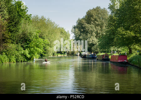 Schmale Boote auf dem Fluss Cam als Menschen neben ihm und ein rudergerät Zeilen durch an einem sonnigen Nachmittag, Cambridge, Großbritannien zu Fuß Stockfoto