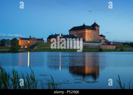 Schöne Aussicht des 13. Jahrhunderts Häme Schloss und seine Reflexionen über Vanajavesi-sees in Hämeenlinna, Finnland, am Abend beleuchtet. Stockfoto