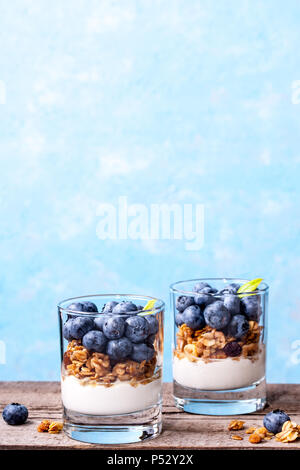 Blueberry Dessert, Käsekuchen, Kleinigkeit, Müsli in einem Glas auf Holz vintage Tabelle mit Rissen. Stockfoto