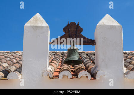 Dach einer alten Kirche Nossa Senhora da Rocha in Porches, Algarve, Portugal. Orange alte Dachziegel. Glockenturm mit einer Glocke. Strahlend blauen Himmel im Hinterg Stockfoto