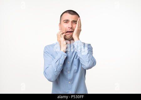 Verzweifelt spanischer Mann im blauen Hemd weint. Er verlor seinen Job oder mit seiner Freundin Pause Stockfoto