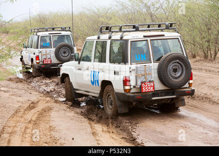 KAKUMA, Kenia - Zwei UN-Land Rover fahren auf einer verregneten Landstraße. Stockfoto