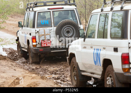 KAKUMA, Kenia - Zwei UN-Land Rover fahren auf einer verregneten Landstraße. Stockfoto