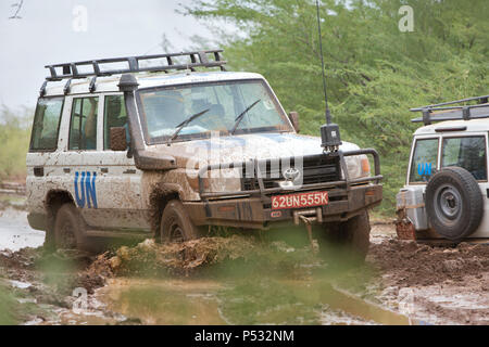 KAKUMA, Kenia - Zwei UN-Land Rover fahren auf einer verregneten Landstraße. Stockfoto