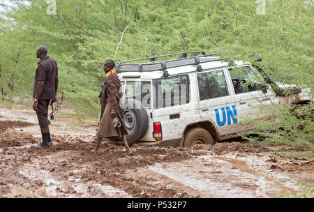 Kakuma, Kenia - ein Turkana Frau geht barfuß auf einer Schotterstraße nasse mit Regen. Stockfoto