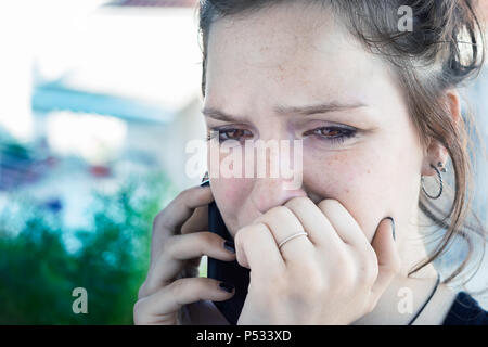 Ein junges Mädchen, das Gespräch per Telefon stehen mit schlechten Nachrichten, schockiert, traurig. Weinen. Stockfoto