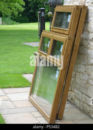 Drei neue doppelt verglaste Massiv eiche Fensterrahmen installiert werden und alte uPVC-Kunststoff Holz Fensterrahmen in einem Heim ersetzen Stockfoto