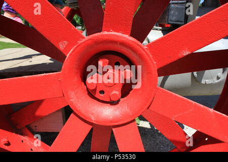 Ein leuchtend rotes, historisches Wagenrad aus Metall. Stockfoto