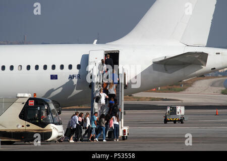 Urlaubsreisen mit dem Flugzeug. Passagiere steigen aus dem Flughafenbus und steigen in ein Düsenflugzeug über eine Rampentreppe ein. EU-Flagge auf dem hinteren Rumpf sichtbar. Stockfoto