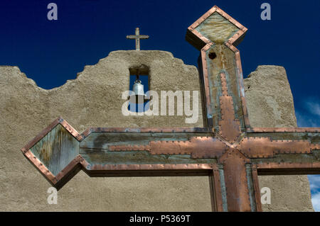 Ein Metall und Holz kreuz schmückt den Innenhof des San Lorenzo Mission in Picurís Pueblo, NM. Stockfoto