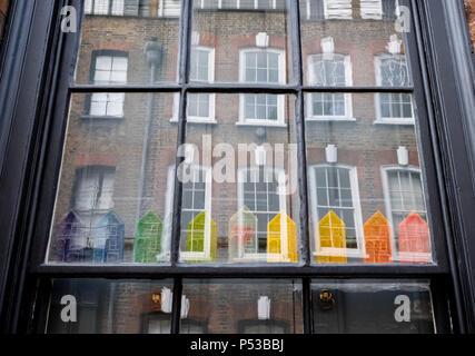 Fenster der Hugenotten Haus auf Princelet Street, Spitalfields, London, anzeigen Reflexionen der Gebäude gegenüber und schrulligen regenbogenfarbenen Modell Häuser Stockfoto