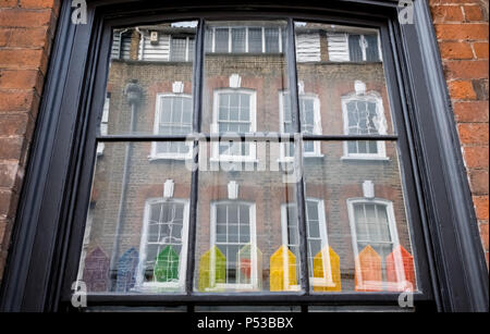 Fenster der Hugenotten Haus auf Princelet Street, Spitalfields, London, anzeigen Reflexionen der Gebäude gegenüber und schrulligen regenbogenfarbenen Modell Häuser Stockfoto