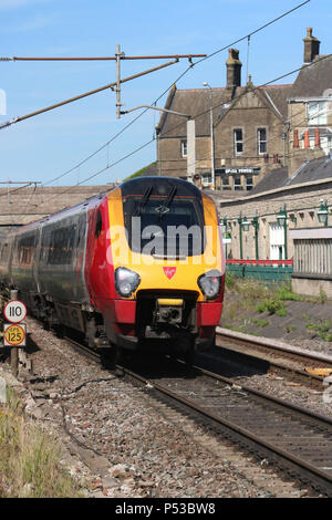 Voyager diesel multiple Unit in Jungfrau Westküste livery durch Carnforth Station auf der West Coast Main Line mit einem express Personenzug Stockfoto