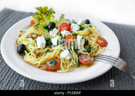 Salat mit Tomate, Gurke und roten Fisch und Scheiben Käse auf einem Teller. Iaelate auf einem weißen Hintergrund. Stockfoto
