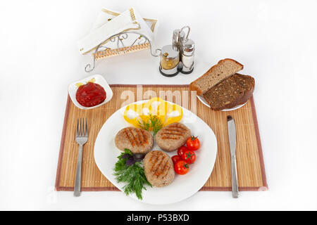 Koteletts mit grünen, Tomaten und Gurken. Mit schwarzen oder weißen Brot und einem Glas Rotwein servieren. Eine perfekte Ergänzung ist eine heiße Soße und Senf. T Stockfoto