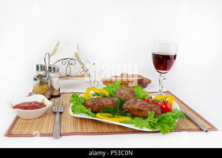 Koteletts mit grünen, Tomaten und Gurken. Mit schwarzen oder weißen Brot und einem Glas Rotwein servieren. Eine perfekte Ergänzung ist eine heiße Soße und Senf. T Stockfoto