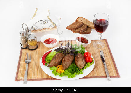 Koteletts mit grünen, Tomaten und Gurken. Mit schwarzen oder weißen Brot und einem Glas Rotwein servieren. Eine perfekte Ergänzung ist eine heiße Soße und Senf. T Stockfoto