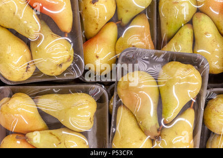 Reife Birnen in durchsichtigen Verpackungen auf Kunststoffpaletten im Schaufenster. Stockfoto