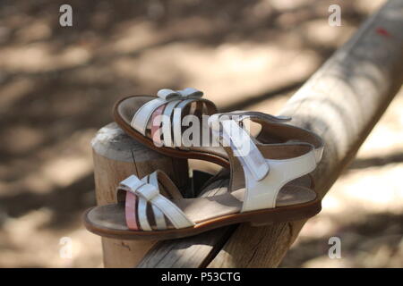 Still life - The Vanishing - ein Paar weiße und rosa Sandalen nach auf einem Zaunpfosten in einem Nationalpark Links, La Mata, Spanien. Sommer 2018. Stockfoto