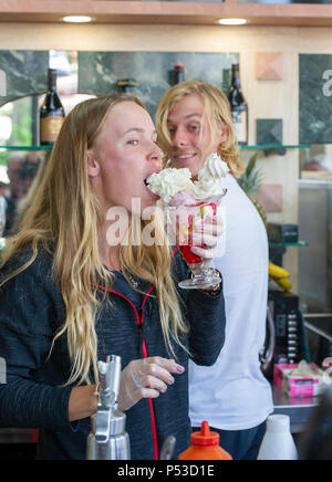 Caroline Wozniacki aus Dänemark von Denis Shapovalov von Kanada beobachtete genießt, und Essen einen Eisbecher in einem lokalen Eisdiele während der Natur Tal internationalen Tennisturnier in Devonshire Park in Eastbourne East Sussex UK. 24. Juni 2018 Stockfoto