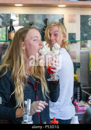 Caroline Wozniacki aus Dänemark von Denis Shapovalov von Kanada beobachtete genießt, und Essen einen Eisbecher in einem lokalen Eisdiele während der Natur Tal internationalen Tennisturnier in Devonshire Park in Eastbourne East Sussex UK. 24. Juni 2018 Stockfoto