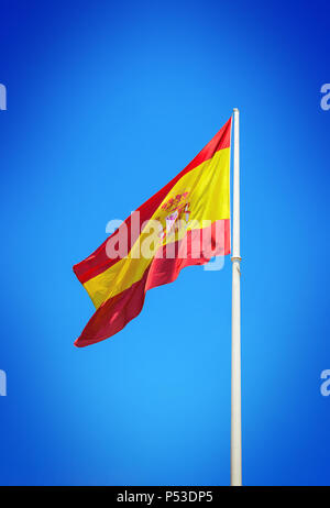 Spanische Flagge schwenkten gegen den klaren blauen Himmel Stockfoto