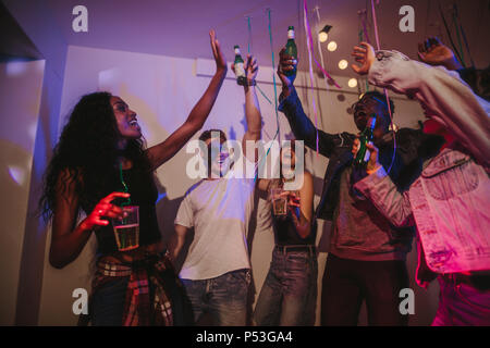 Freunde toasten Getränke an einer Party. Junge Männer und Frauen, die Spaß an einem bunten House Party mit Konfetti. Stockfoto