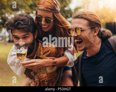 Fröhlicher junger Menschen Spaß draußen im Park. Männer und Frau huckepack und Bier. Stockfoto