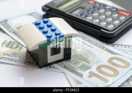 Das Konzept der Gehäuse Kreditvergabe. Geld, Taschenrechner, Spielzeug, Haus Stockfoto