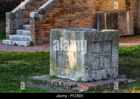 Dekorative Vase aus Beton mit religiösen Symbolen, stehend auf einem grünen Rasen Stockfoto