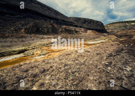 Alte Grube Rückstände mit saurem Wasser strömen durch orange Mineralien, Spanien Stockfoto