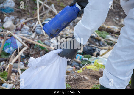 Ein freiwilliger Mann im weißen Schutzanzug sammelt Müll. Hand hautnah Stockfoto