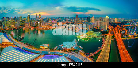 Breites Panorama bei Sonnenuntergang und blaue Stunde von Singapur Marina Bay mit beleuchteten Wolkenkratzer des Financial District in der Innenstadt der Stadt. Singapur Stadtbild Luftaufnahme. Stockfoto