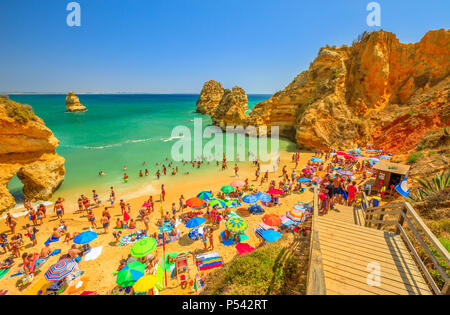 Lagos, Portugal - 21 August 2017: menschenmenge Sonnenbaden und genießen unter bunten Sonnenschirmen in beliebten Praia do Camilo in der Nähe von Ponta da Piedade. Sommer Urlaub in Algarve, Portugal, Europa Stockfoto