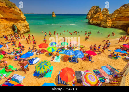 Lagos, Portugal - 21 August 2017: viele Menschen Sonnenbaden und genießen unter bunten Sonnenschirmen auf der beliebten Praia do Camilo Strand in der Nähe von Ponta da Piedade. Sommer Urlaub in der Algarve, Portugal. Stockfoto