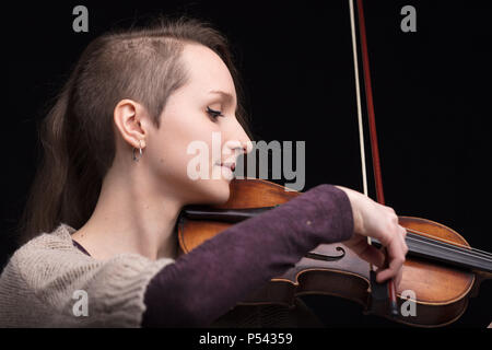 Junge Frau mit der Hälfte ihrer Haare rasiert während der Wiedergabe einer barockvioline auf schwarzem Hintergrund Stockfoto