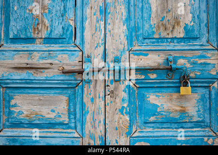 Holz- blaue Tür geschält, gesperrt, für Kulisse im Alter. Alte Eingang mit rostiger Riegel und Vorhängeschloss. Nahaufnahme. Stockfoto