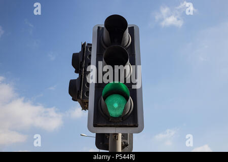 Grüne Ampel isoliert. Signal, dass es sicher ist, den Weg zu gehen. Blauer Himmel mit einigen Wolken Hintergrund. Close Up unter Ansicht. Stockfoto