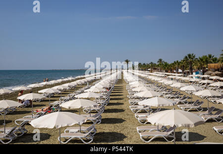 Mackenzie Sandstrand in Larnaca, Zypern. Liegestühle und Sonnenschirme neben Meer. Blauer Himmel Hintergrund, Detailansicht. Stockfoto