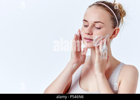 Teenager Hautpflege. Schöne Mädchen im Teenageralter mit Sommersprossen und blaue Augen mit Foaming Cleanser. Gesicht waschen Konzept auf weißem Hintergrund. Stockfoto